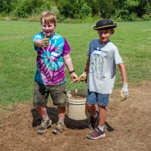 Campers carry a bucketful of excavated dirt to the screening area.
