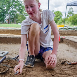 A camper troweling away at one of the squares in the clay borrow pit excavations.