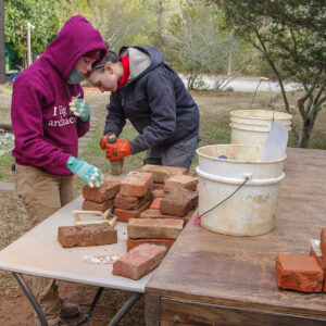 Staff Archaeologist Natalie Reid and Site Supervisor Anna Shackelford clean bricks prior to their examination by the Colonial Williamsburg masons.