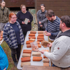 Members of the Jamestown Rediscovery team and Colonial Williamsburg Masonry Trades team discuss bricks from the Governor's Well. (L-R) Director of Archaeology David Givens, Site Supervisor Anna Shackelford, Brickmaker's Apprentice Madeleine Bolton, Collections Assistant Lauren Stephens, Associate Curator Emma Derry, Masonry Trades Manager Josh Graml, and Journeyman of Masonry Trades Kenneth Tappan.
