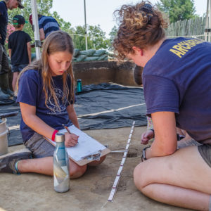Archaeologist Brenna Fennessey teaches feature mapping techniques with a camper.