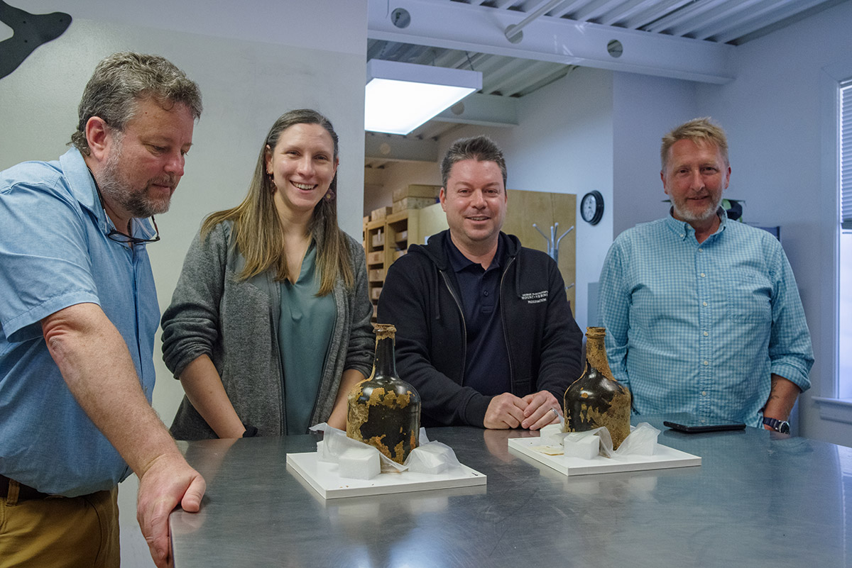 (L-R) Senior Conservator Dr. Chris Wilkins, Historic Preservation at Mount Vernon's Curator of Preservation Collections Lily Carhart and Principle Archaeologist Jason Boroughs, and Senior Conservator Dan Gamble with the Mount Vernon cherry bottles.