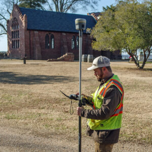 An employee of VHB surveys the area around the Memorial Church as part of an effort to develop drainage around the structure.