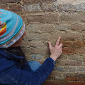 Senior Staff Archaeologist Mary Anna Hartley points to a brick in the Church Tower that bears a fingerprint.