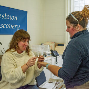 Senior Curator Leah Stricker examines the partial Turk's head pipe brought in from the Godspeed Cottage excavations by Archaeological Field Technician Hannah Barch.