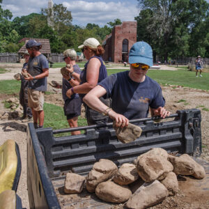 The archaeological team removes cobbles marking the location of one of the "fair rows of houses" in preparation for excavating three of the burials underneath it.