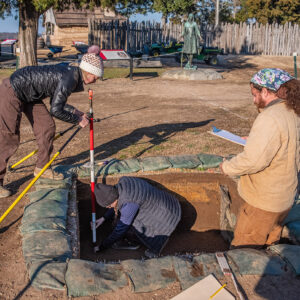 Archaeological Field Technician Katie Griffith, Archaeological Intern Aubrey Strand, and Archaeological Field Technician Josh Barber prepare for a survey of features inside an excavation square.