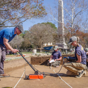 Director of Archaeology Sean Romo and Archaeological Field Technician Katie Griffith conduct a GPR survey of one of the burials in the North Church excavations.
