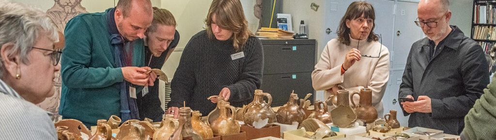 The "Bartmann Goes Global" group discusses Jamestown's Bartmann jug collection with staff.
