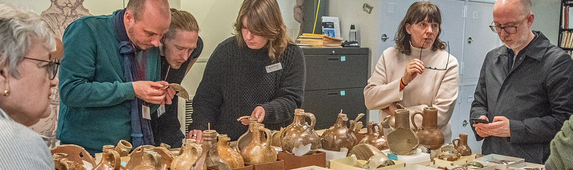 The "Bartmann Goes Global" group discusses Jamestown's Bartmann jug collection with staff.