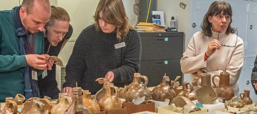 The "Bartmann Goes Global" group discusses Jamestown's Bartmann jug collection with staff.
