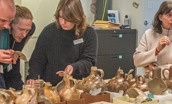 The "Bartmann Goes Global" group discusses Jamestown's Bartmann jug collection with staff.