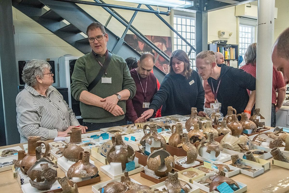 The "Bartmann Goes Global" group discuss Jamestown's Bartmann jug collection with staff.