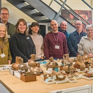 The "Bartmann Goes Global" group and staff take a photo with Jamestown's Bartmann jug collection.
