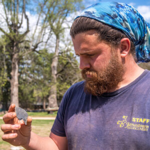 Archaeological Field Technician Josh Barber examines the slate piece he found in the North Church excavations.