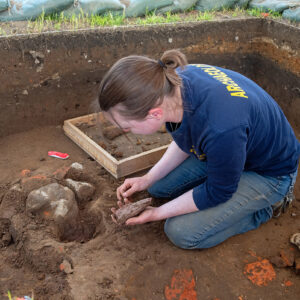 Staff Archaeologist Natalie Reid excavates cobbles from the top of the well