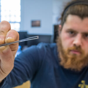 Archaeological Field Technician Josh Barber displays a tiny bead he found while picking through excavated material from a past dig.