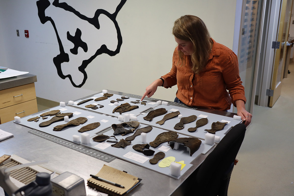 Curator Leah Stricker examines shoes found in the fort's second well.