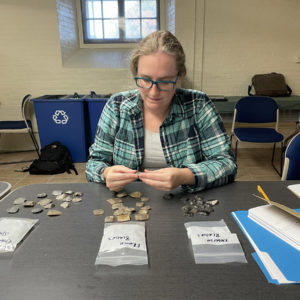 Assistant Curator Janene Johnston inspects different types of gunflints at the 2022 Archeology of Firearms conference.
