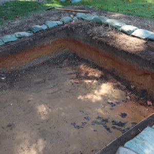 The excavations at the 1941 archaeological site. The orange layer is the soil preparation for the 1950s road and the gray layer beneath it is the fill from the 1941 excavations.