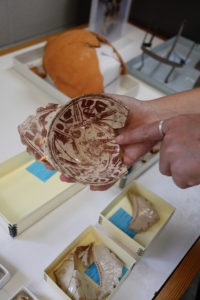Curator Leah Stricker holds a Spanish Lustreware bowl featuring a bird and flowers.