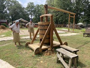 Members of Colonial Williamsburg's brickyard team with their pug mill. The wooden harness at right is attached to a beast of burden that walks in a circle to power the mixer.