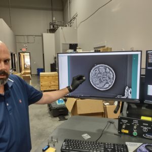 Director of Collections & Conservation Michael Lavin holds a rusted King's Touch Token next to an X-ray of the object.