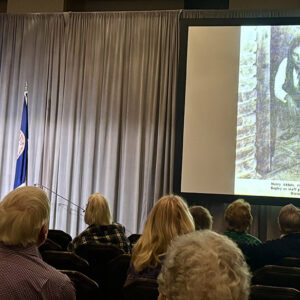 Jamestown Rediscovery Senior Curator Merry Outlaw and Jamestown-Yorktown Foundation Senior Curator Bly Straube present on the upcoming exhibit "Following the Dragon". On the screen is an image of them from an earlier time.