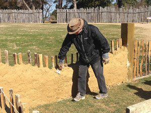 Archaeologist applying mud mixture to a low wall