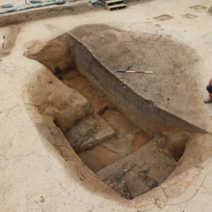 Aerial view of an archaeologist kneeling next to an excavated cellar