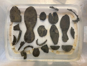 Leather shoe fragments excavated from the Governor's Well in water after excavation, fall 2023