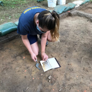 Archaeologist comparing a soil sample to a color chart