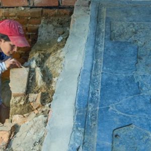 Archaeologist excavates under granite tombstone