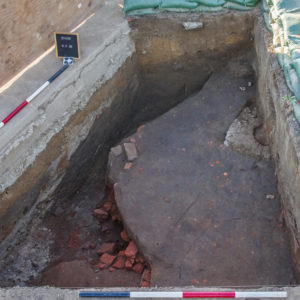 view looking down into a large rectangular excavation unit containing a brick foundation