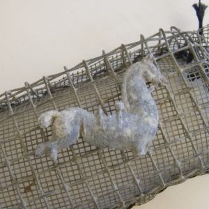 Toy horse laying in a wire screen