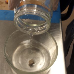 Solution being poured into a container with a lead die