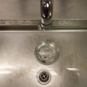 Container with a lead die under a faucet