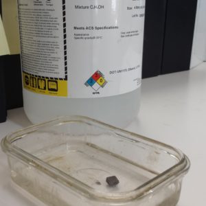 Bottle of solution and a lead die being soaked in a glass container