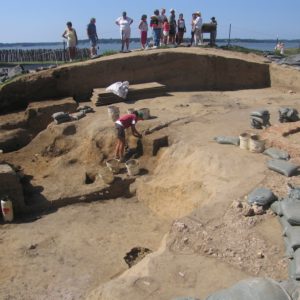 Visitors watching an archaeologist excavating