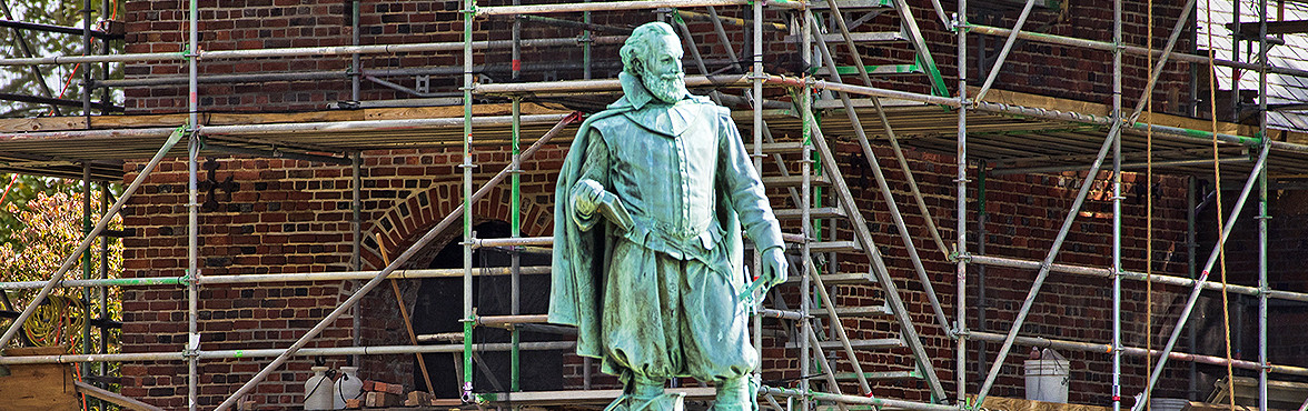 John Smith statue and a brick church tower surrounded by a scaffold in the background