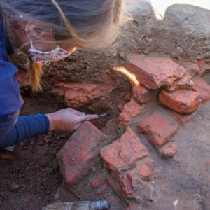 archaeologist excavating a small pile of bricks in a unit