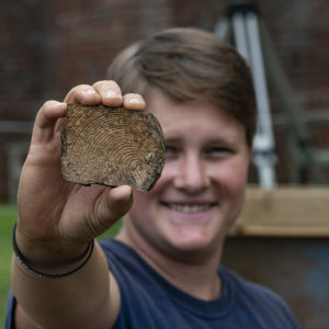 Staff Archaeologist Caitlin Delmas holds a ceramic sherd found in the north Church Tower excavations.