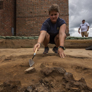 Staff Archaeologist Caitlin Delmas points to a sherd of ceramic found in the north Church Tower excavations.