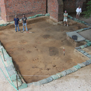 aerial view of crew members standing in an excavation unit lined with sandbags next to a brick church