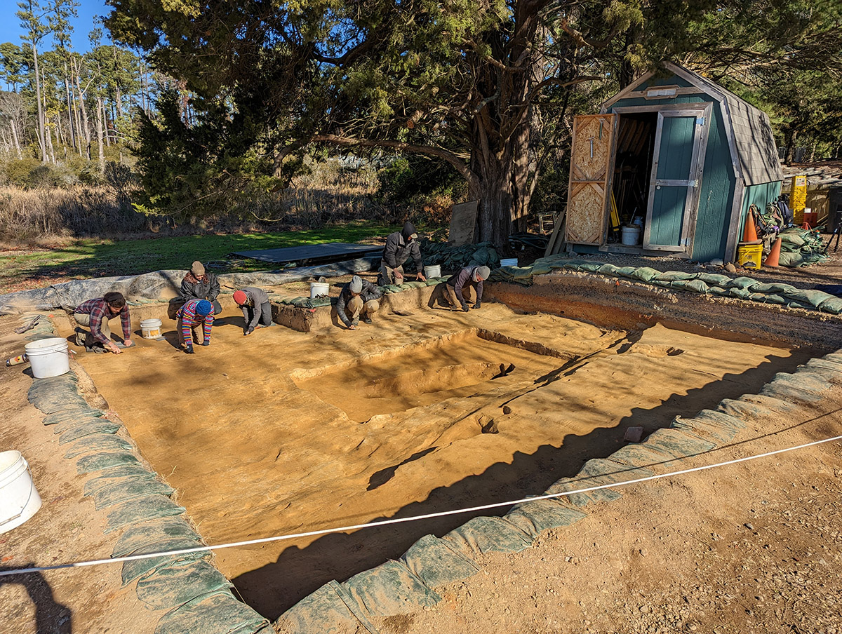 The archaeological team prepares the "burial" north field excavation squares for record photography. The "burial" feature can be seen in the center of the photograph.