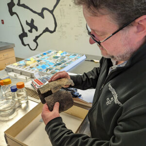 Conservator Dr. Chris Wilkins examines a Virginia Indian pot, the adhesive of which has weakened.
