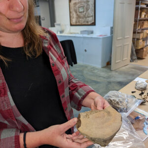 Curator Leah Stricker holds a whale vertebra fossil.