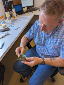Senior Archaeological Conservator Dan Gamble holds a fragment of a bell he is conserving. It was found during excavations of the brick church that was in use from approximately 1639 until the 1750s.