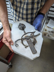 Conservator Don Warmke holds the sword he's been conserving. It was found in the Governor's Well and is unusually complete by Jamestown standards, having a partial blade, hilt, handle, and pommel.