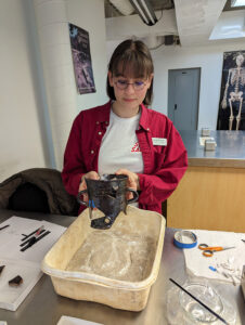 Conservation Intern Jackie Bucklew holds the Essex post-medieval blackware vessel she is mending.